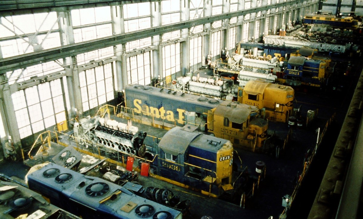 Blue and gold Santa Fe diesel locomotives in a row at a workshop