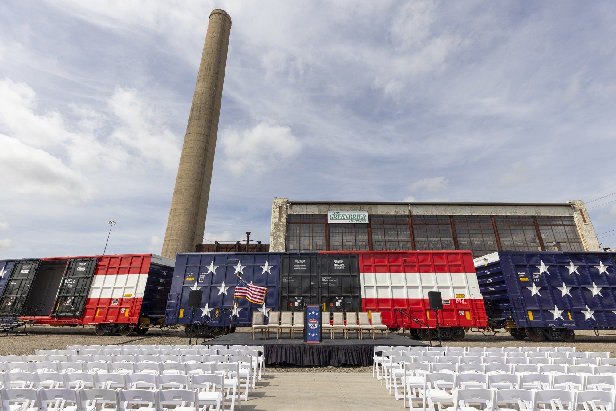 3 boxcars painted in patriotic colors in front of a manufacturing facility